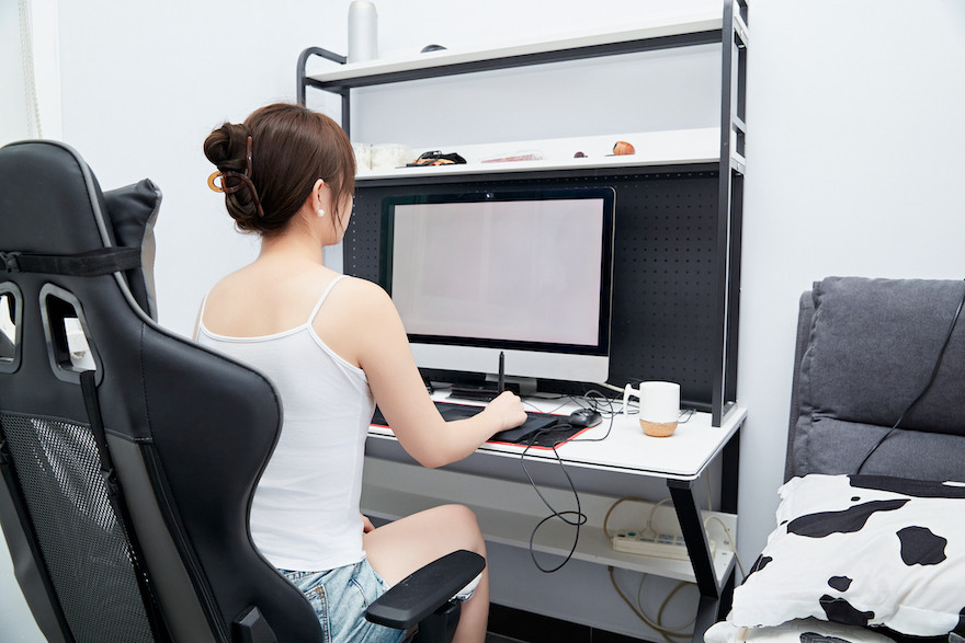 An Asian woman working from home on a computer